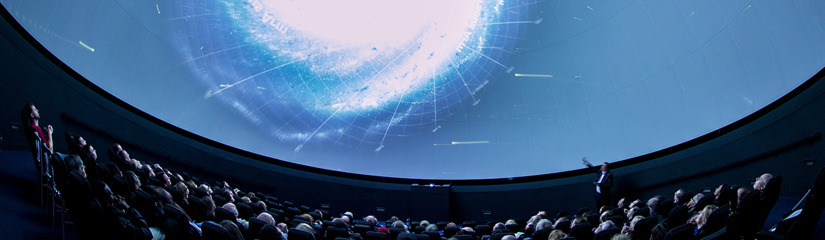 a projection of a galaxy on the full dome planetarium whilst an audience watch and listen to an astronomer