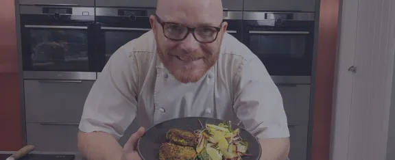 Gary Maclean smiles as he shows off a plate of spiced quinoa cakes