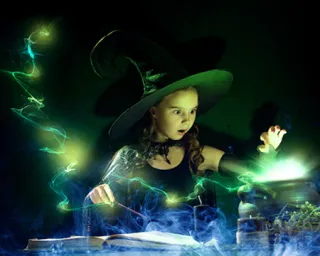 An eerie green glow lights up a witch's hand over a cauldron