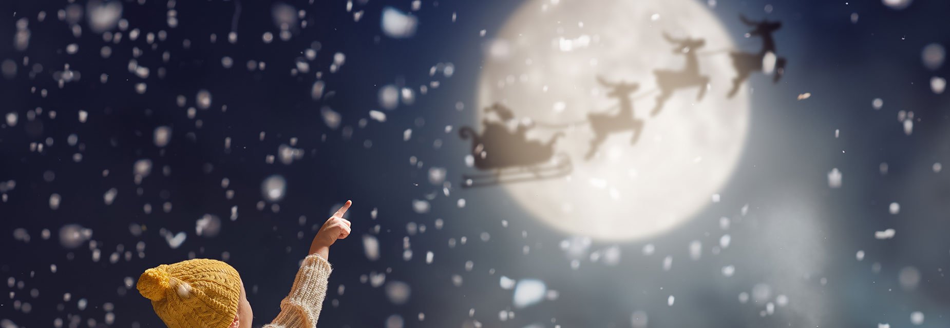 child pointing at moon as santa flies past