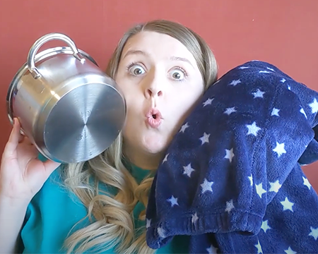 Claire holds up a cooking pot and blanket to her cheeks