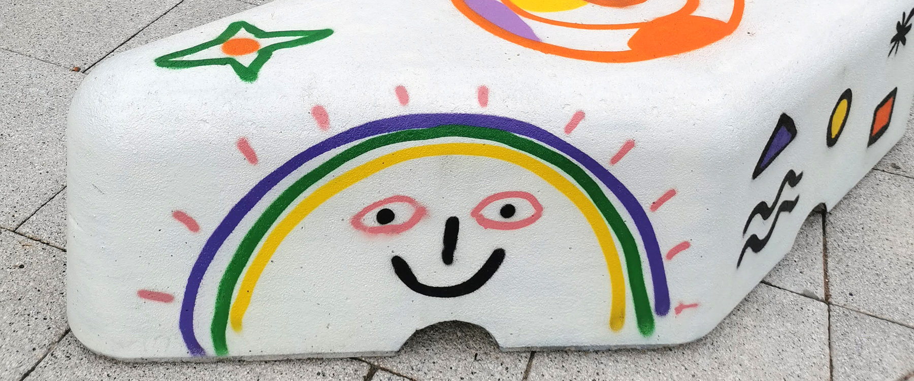 A colourfully-painted bollard has a planet with a smiling face