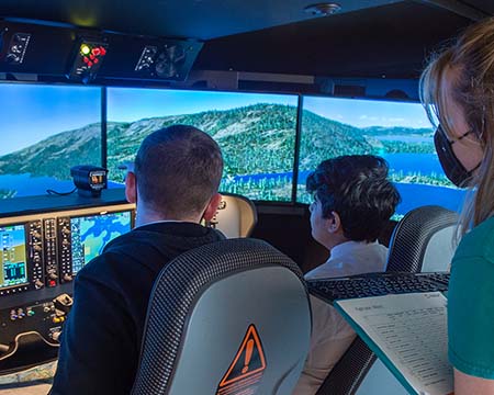 Two students at the controls of a flight simulator under instructor from science centre flight crew