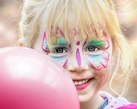 Little girl with butterfly face paint and pink balloon 