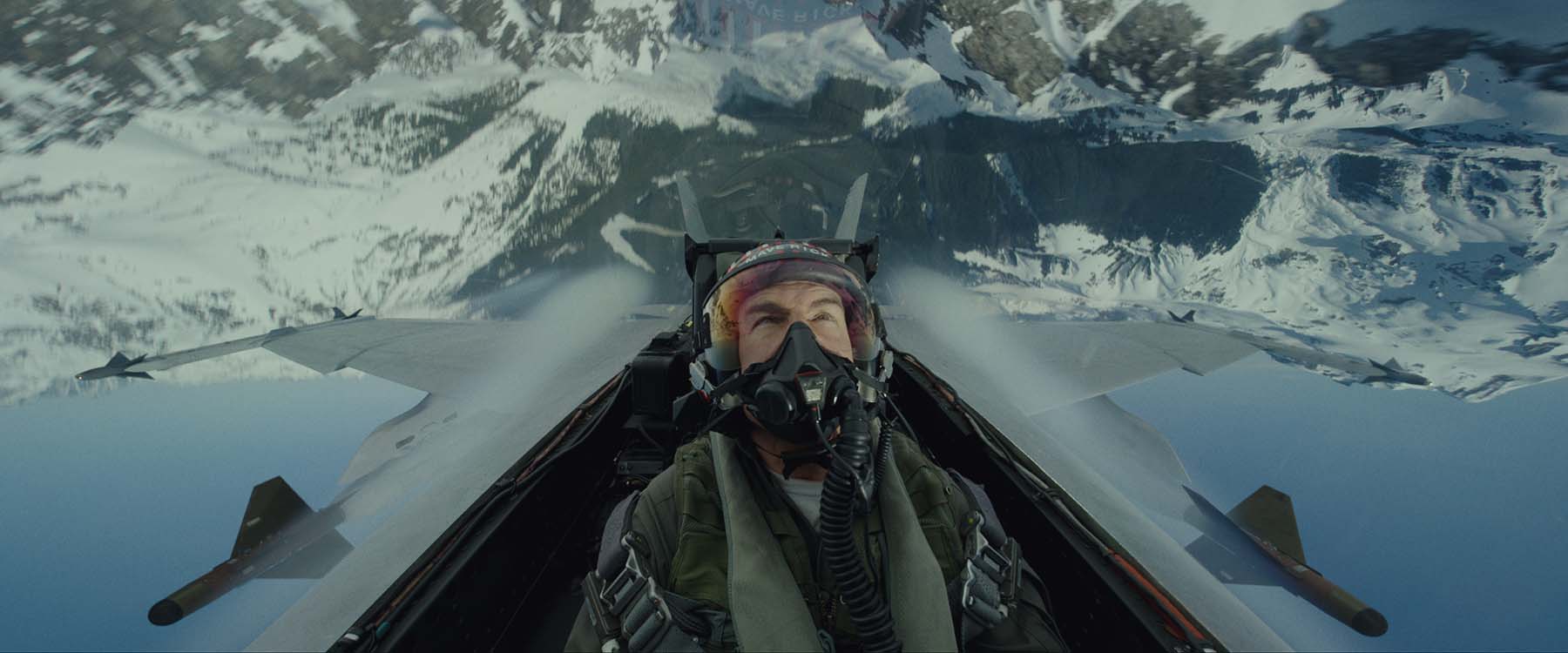 Tom Cruise in cockpit of plane with sky behind him 