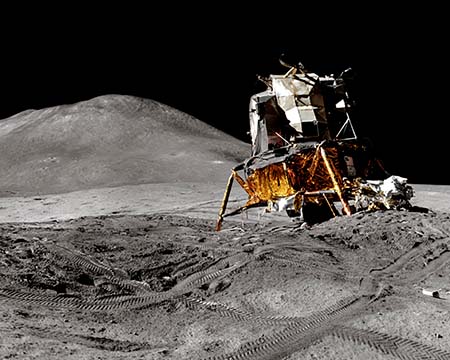 A lunar vehicle on the surface of the moon. There are tracks on the surface of the Moon and in the distance a hill. Image credit: Andy Saunders / NASA