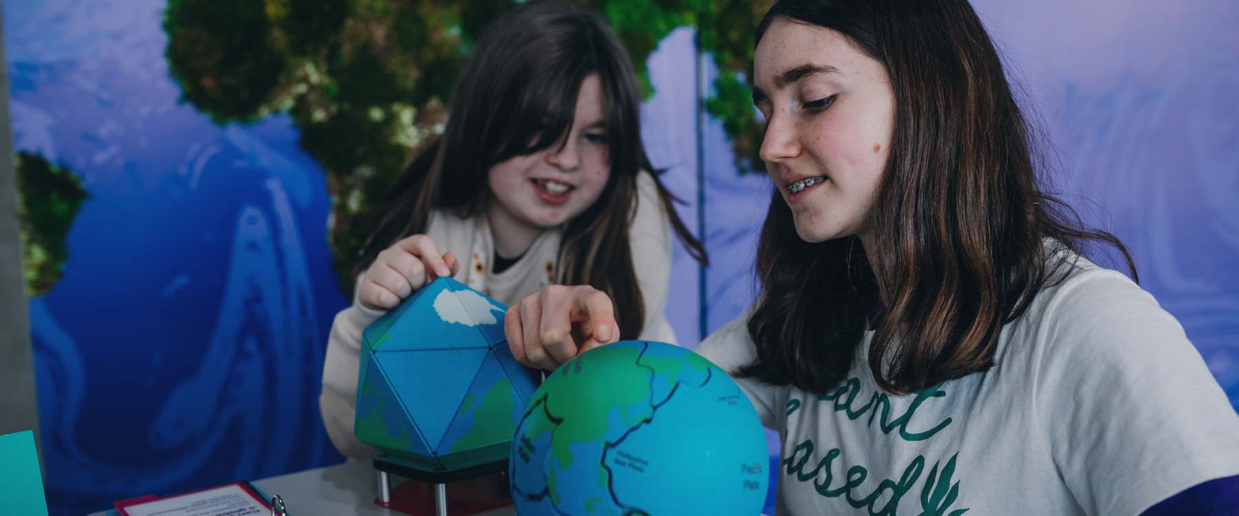 Two young people explore the pieces of a 3D jigsaw globe.