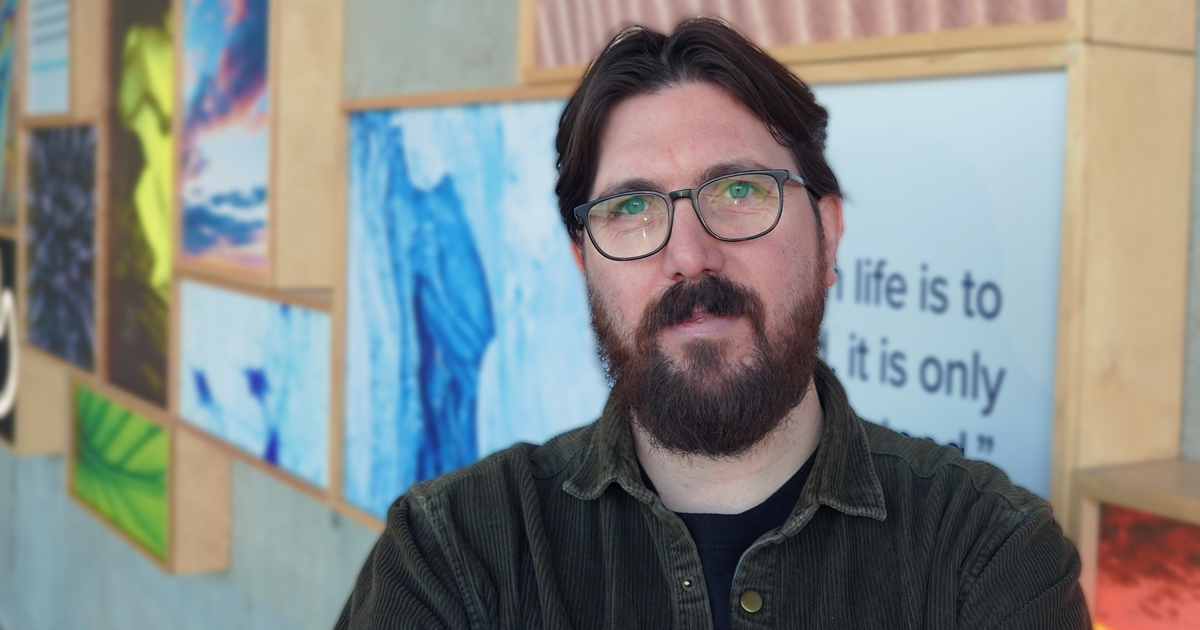 Alex Chandler standing in front of the Wonder Wall at the science centre