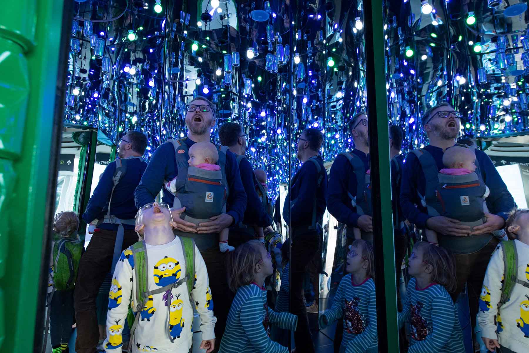 A family look up into the mirrored interior of the Every Can Counts exhibit and are reflected in the surfaces