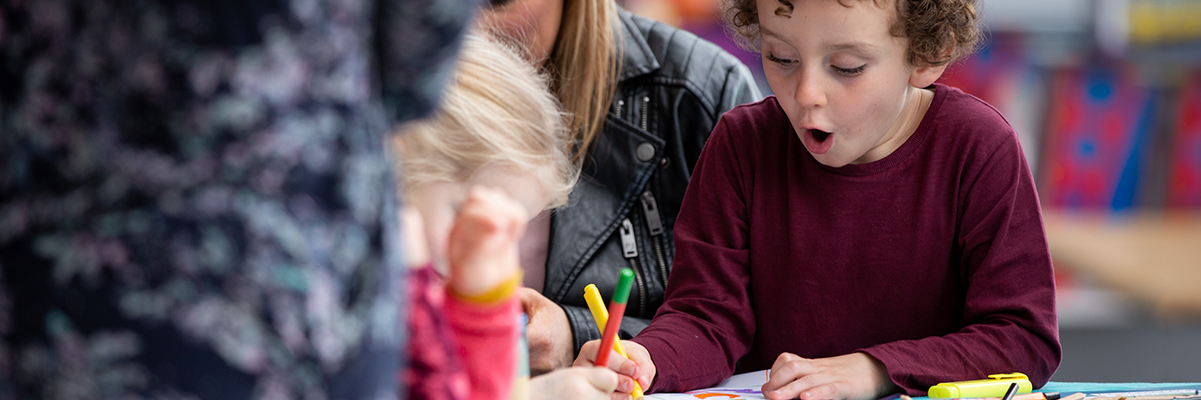 Child excitedly drawing in a workshop