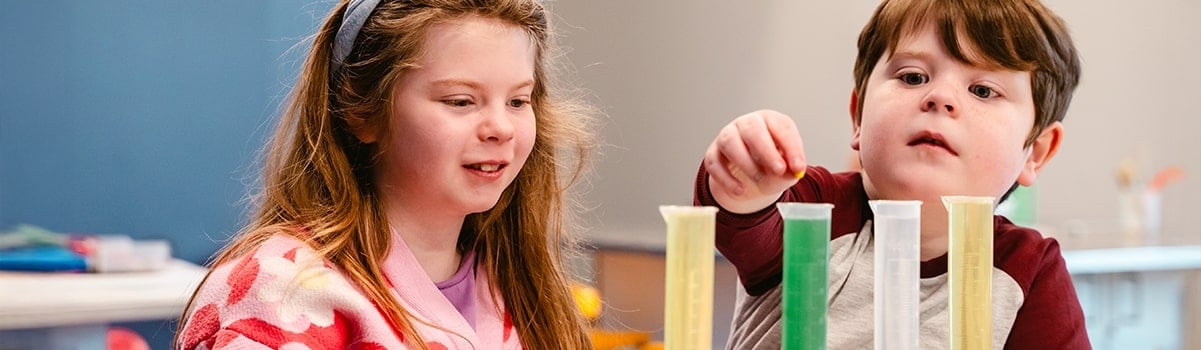 two children taking part in an experiment involving four test tubes