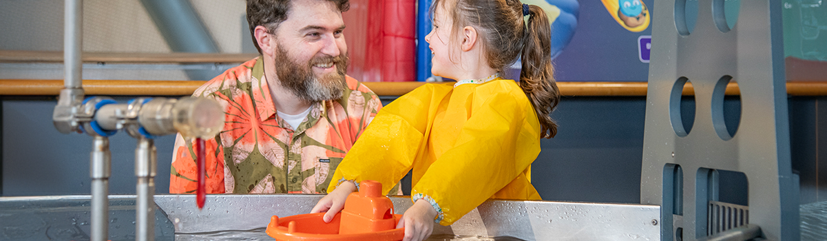 a child and parent play in the water exhibit in the Big Explorer