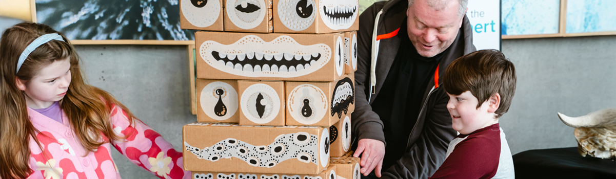 two children and an adult play giant jenga in the hive