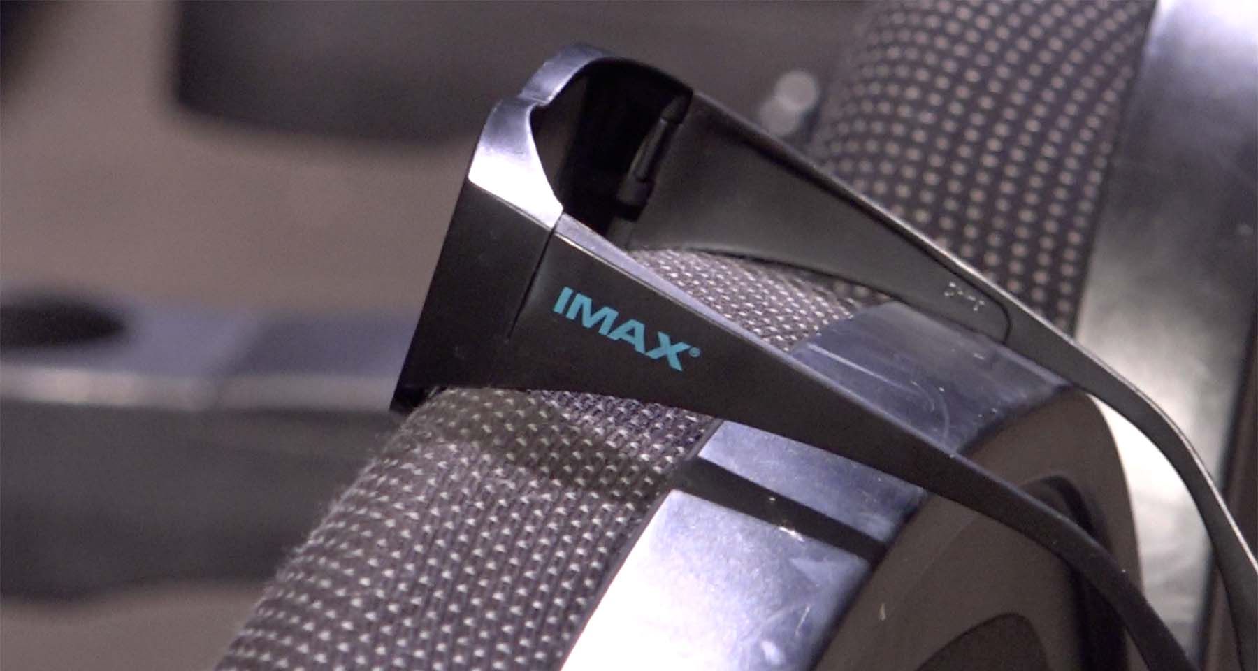 A pair of IMAX 3D glasses rest on the back of a seat in the theatre
