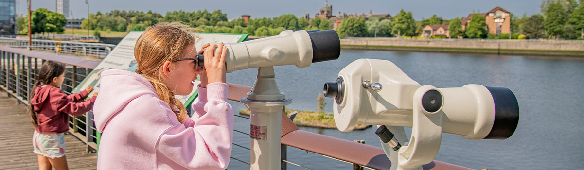 two children looking at the floating wetlands through the binoculars