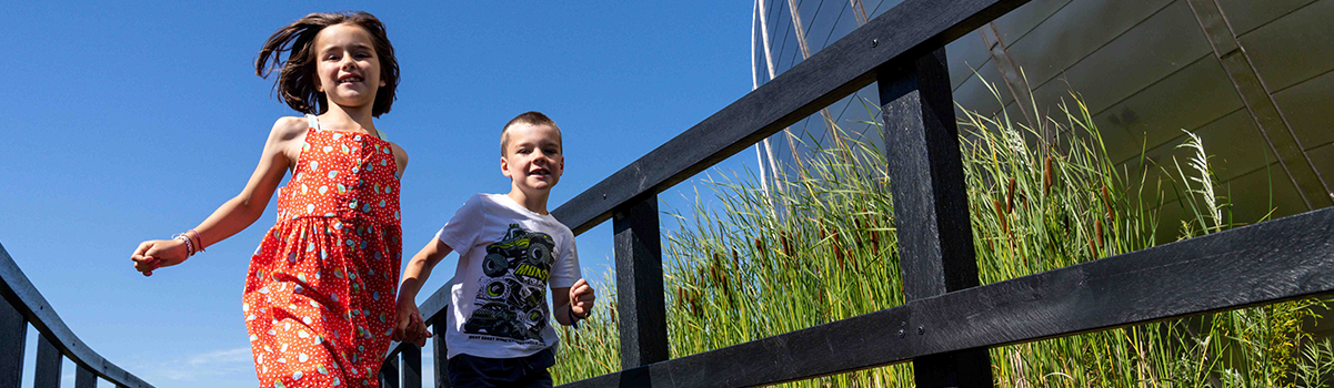 Two children running beside the wetland moat