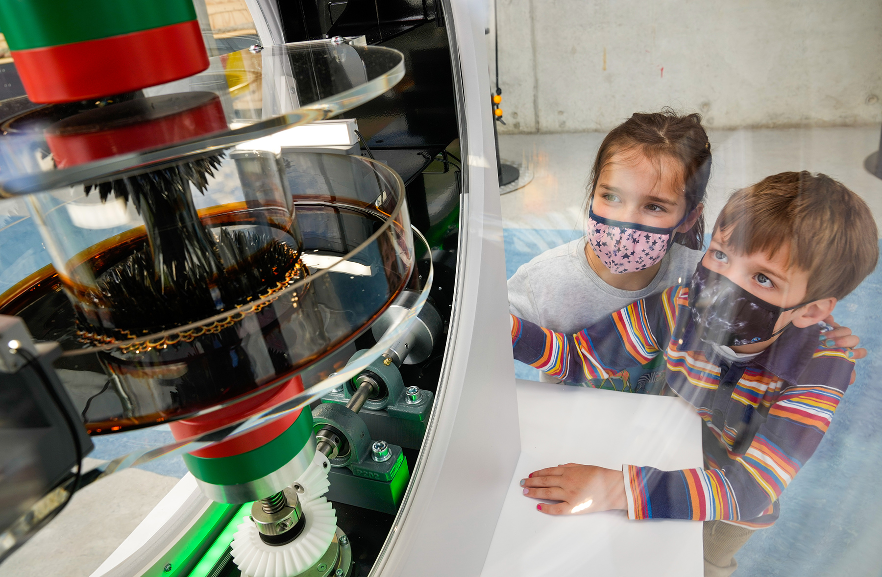 Two children watch the changing shape of a ferrofluid