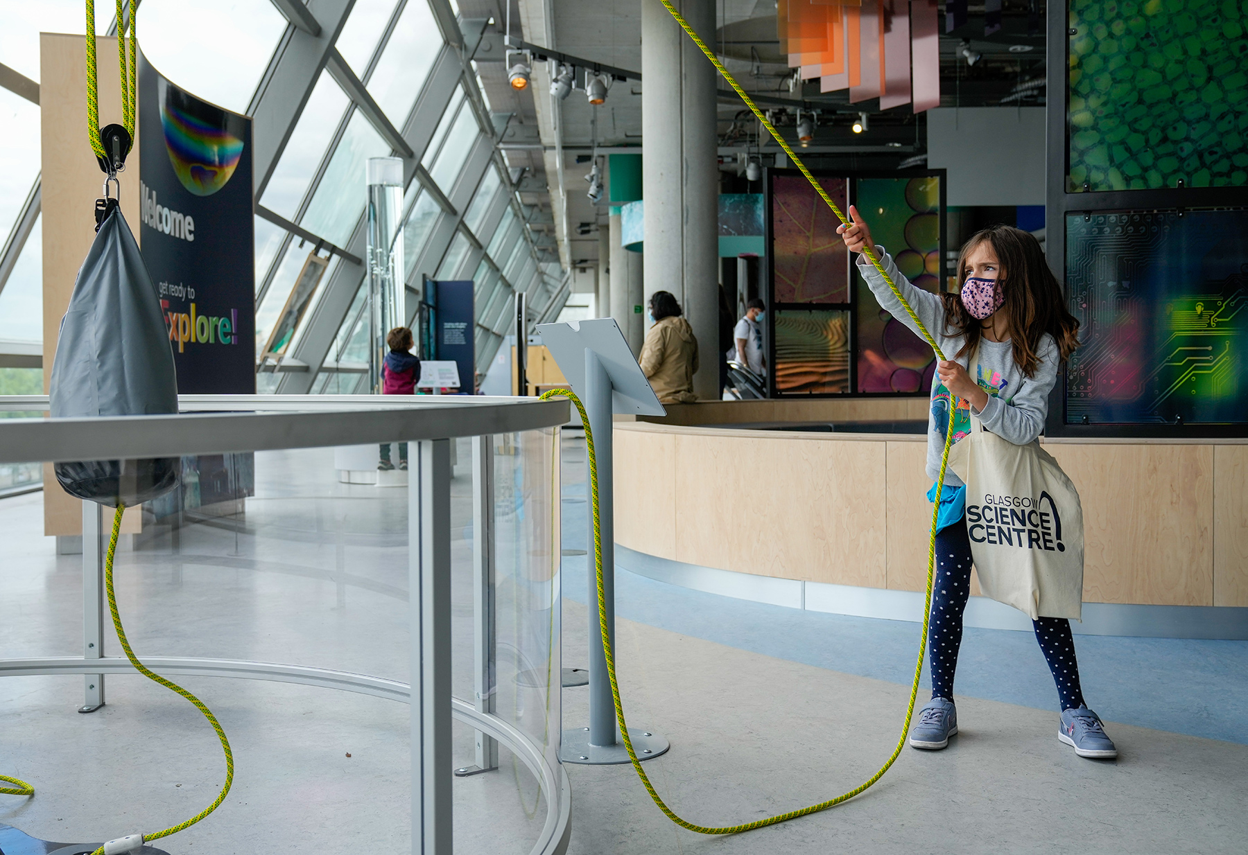 A young person pulls a rope connected through a series of pulleys to lift a heavy weight