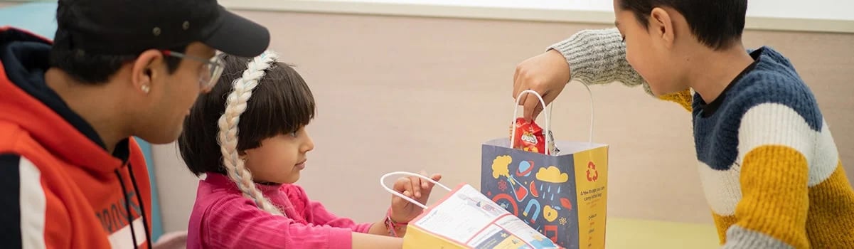 A family open a kids grab bag for lunch in the Cafe