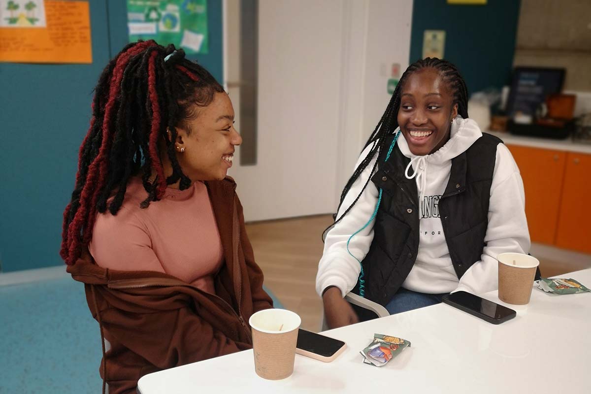 Two young people from our Earth Allies group are smiling whilst seated at a table in The Bothy.