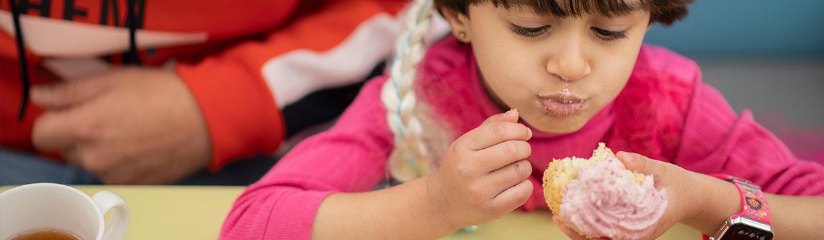 a child has a mouthful of cupcake in the cafe