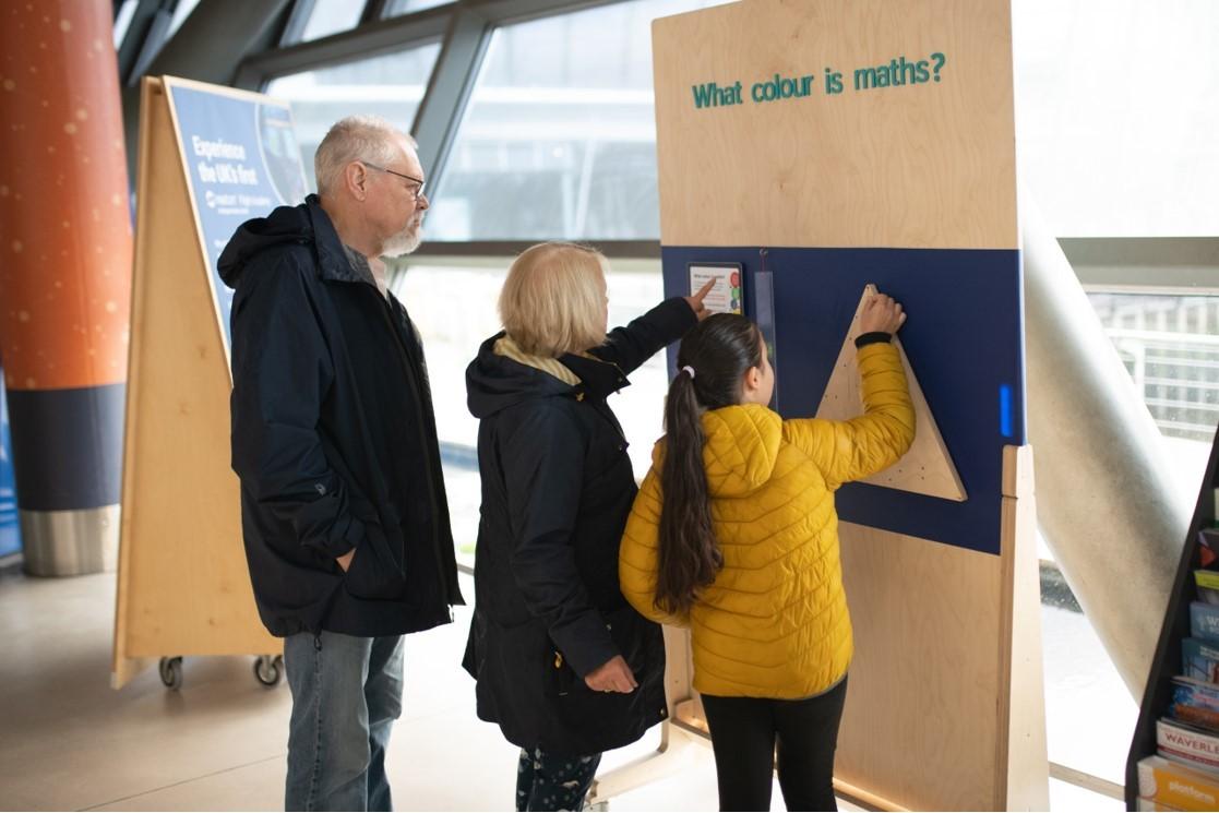 Two people stand at an exhibit with a Sierpiński triangle