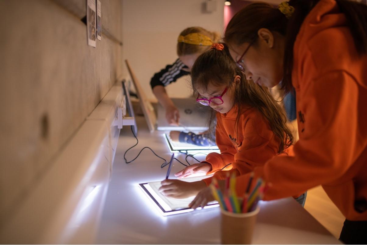 people painting at a desk using light boxes to trace patterns