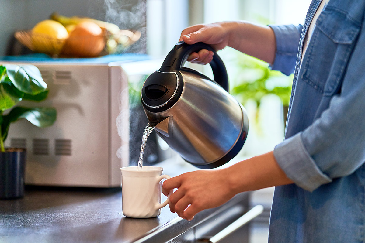 Pouring water from a kettle to make a cup of tea