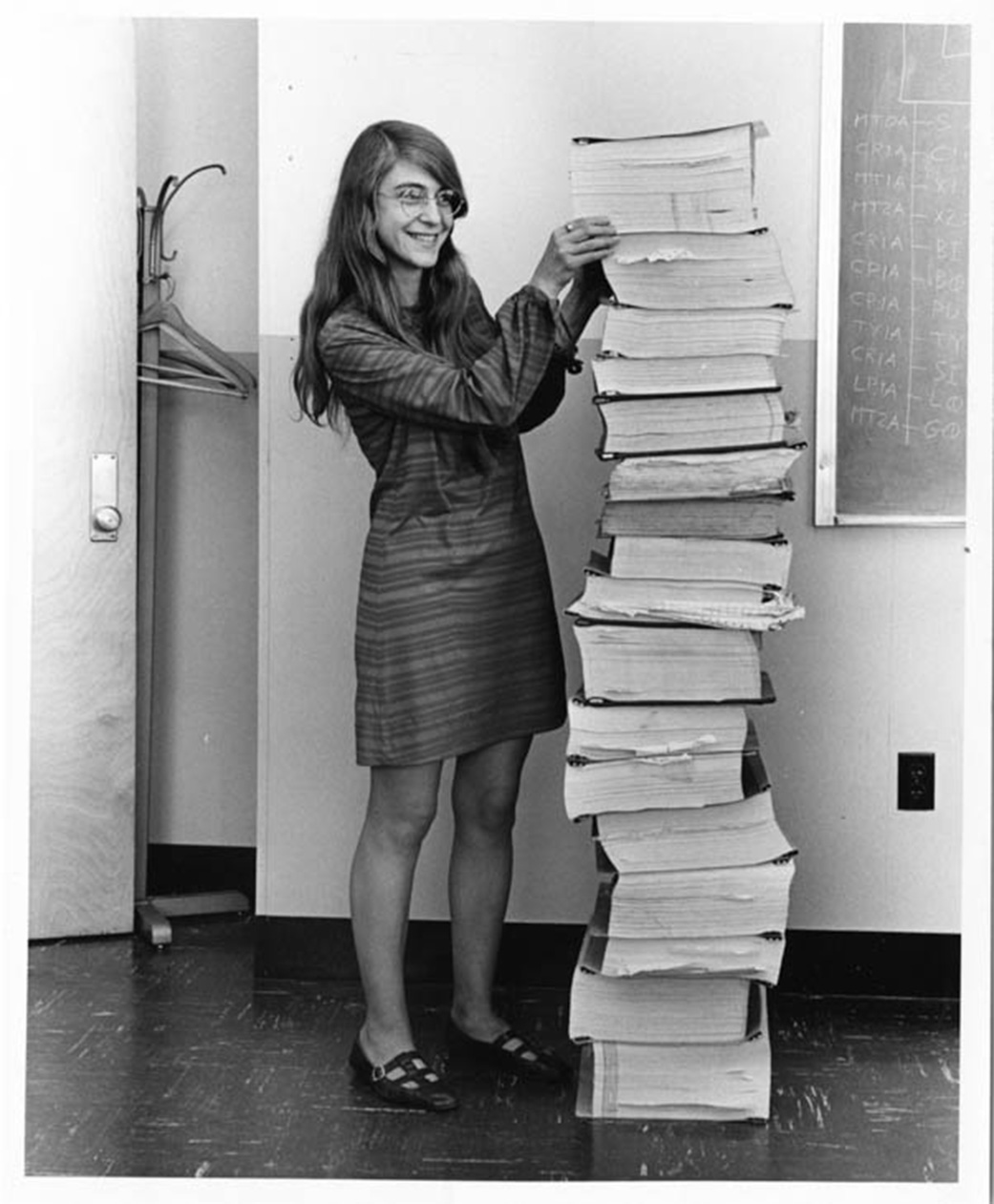 Margaret Hamilton stands next to a stack of Apollo Guidance Computer source code.