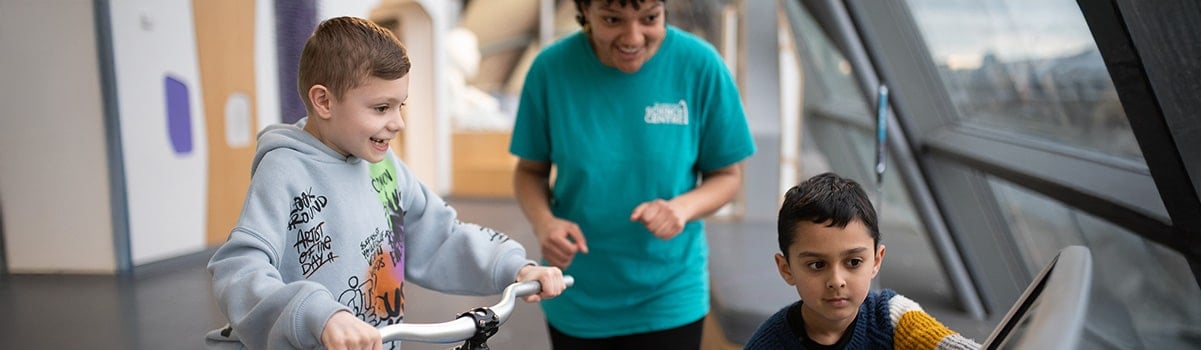 two children and a science communicator interact with the bicycle in Bodyworks