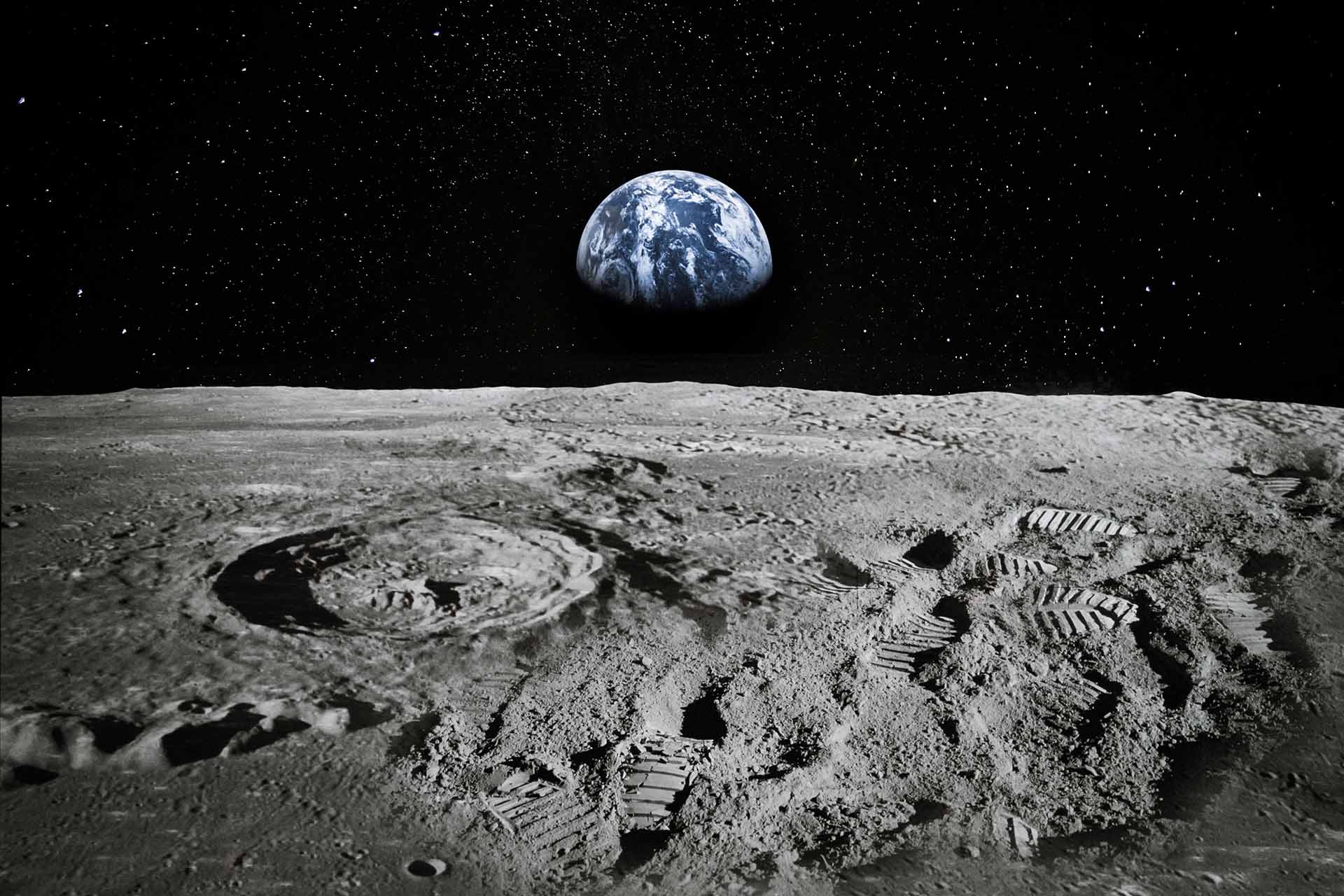 The Earth rises into the horizon in space as viewed from the surface of the Moon.