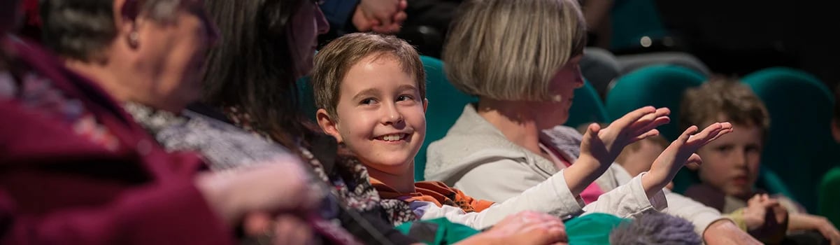 An audience smile as they warm up for a science show.