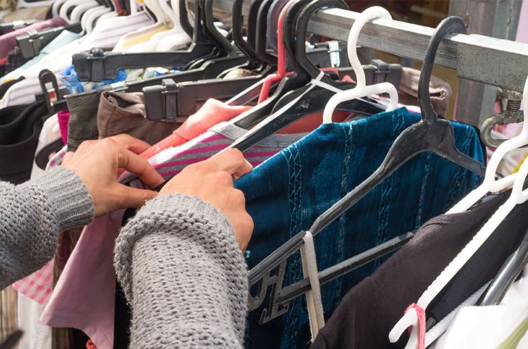 A person looks through a rail of second hand clothing