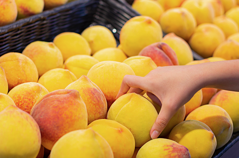 Person picks a piece of fruit from a stack of fruit in a supermarket