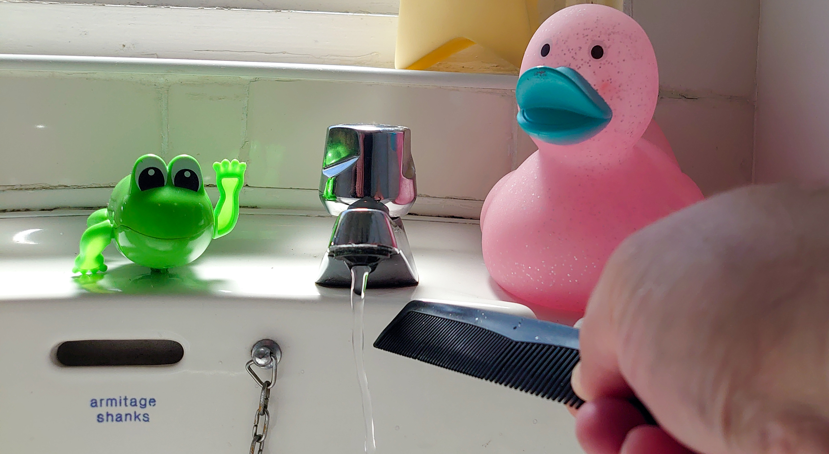 Water from a tap bends towards a plastic comb