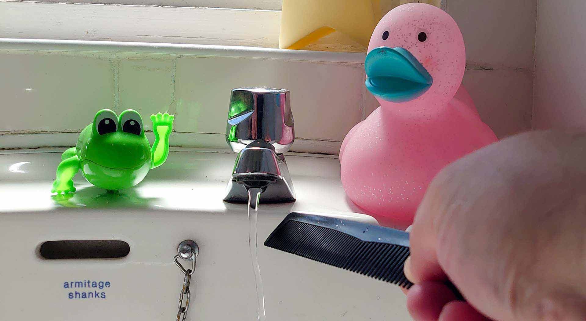 Water flows from a sink tap and a bend is seen as a plastic comb is placed close to the stream