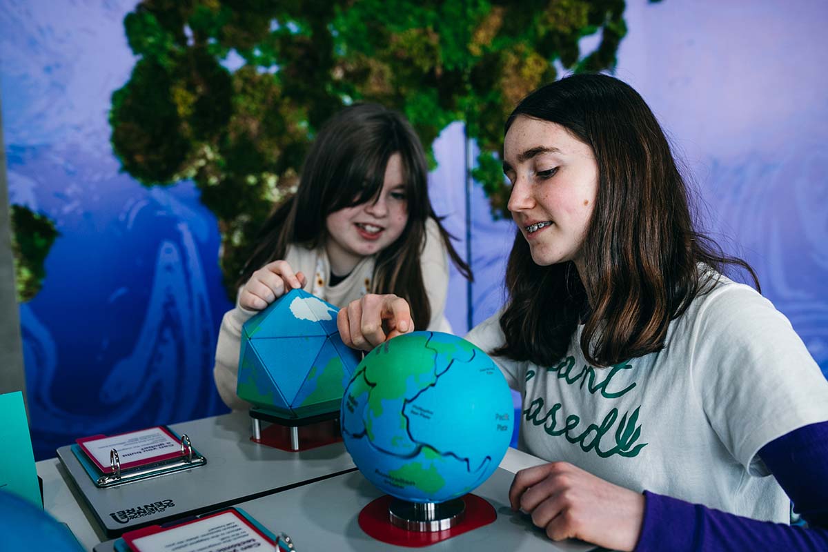 Two young people explore the pieces of a 3D jigsaw of Earth.