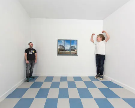 A girl appears much taller than a man in a forced perspective room
