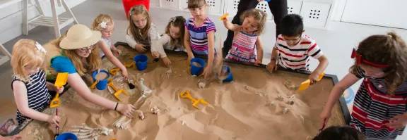 Boys and girls dig for dinosaurs