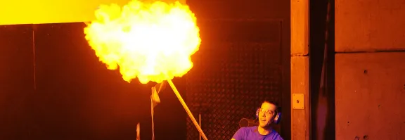 A science communicator ignites a hydrogen balloon which releases a ball of heat and light.