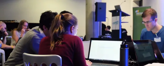 Delegates seated at laptops participating in the hackathon