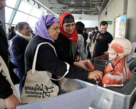 A group of visitors exploring an interactive exhibit of a head.