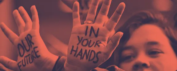 A person with "Our Future In Your Hands" written on their hands