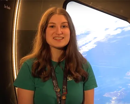 Presenter Natalie sits in front of the Cupola exhibit at Glasgow Science Centre with a view of Scotland/
