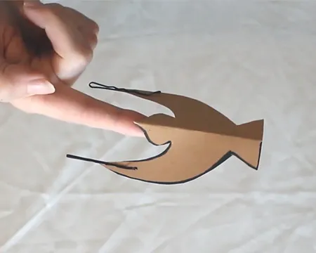 A cardboard bird balancing on a finger