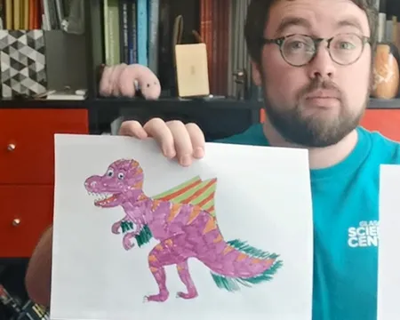 Presenter Sam holds up dinosaur designs