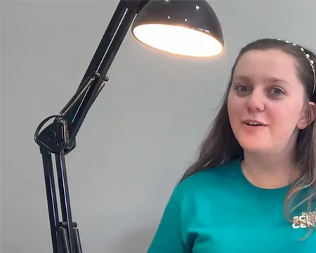 Presenter Caitlin sits beside an illuminated lamp