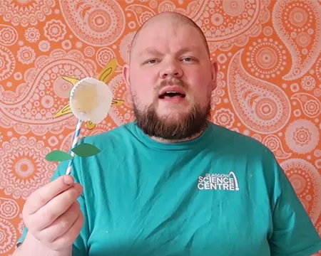 Presenter CJ holds up a paper flower