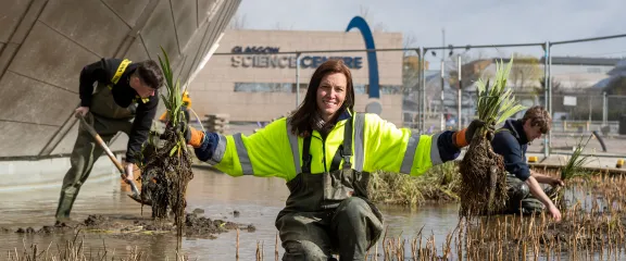 Dr Gillian Lang holds plants in the moat around Glasgow Science Centre