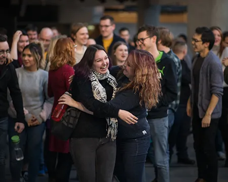 Two GSC staff smile in a friendly embrace